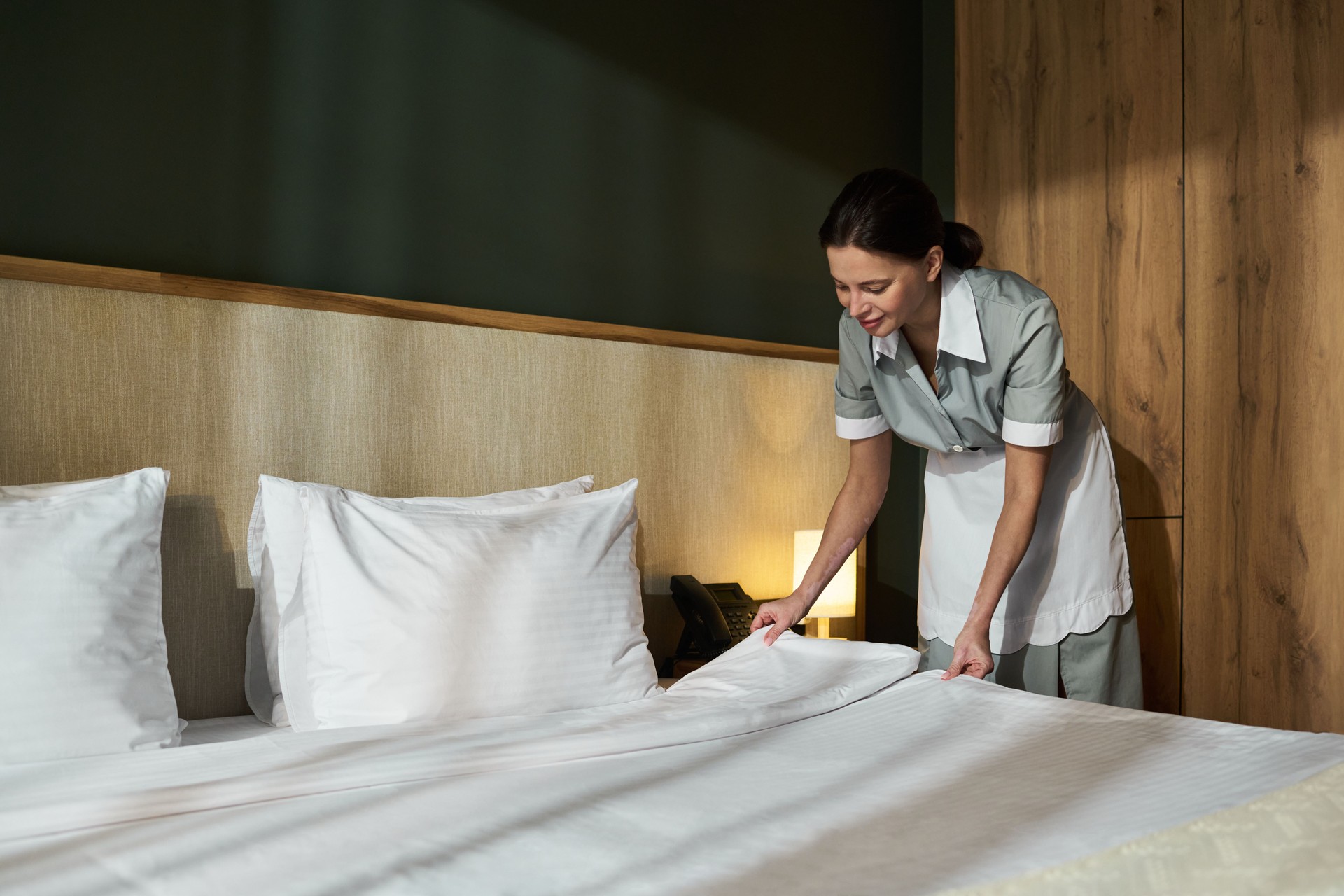 Housekeeping Woman Tidying Up Bed in Hotel Room