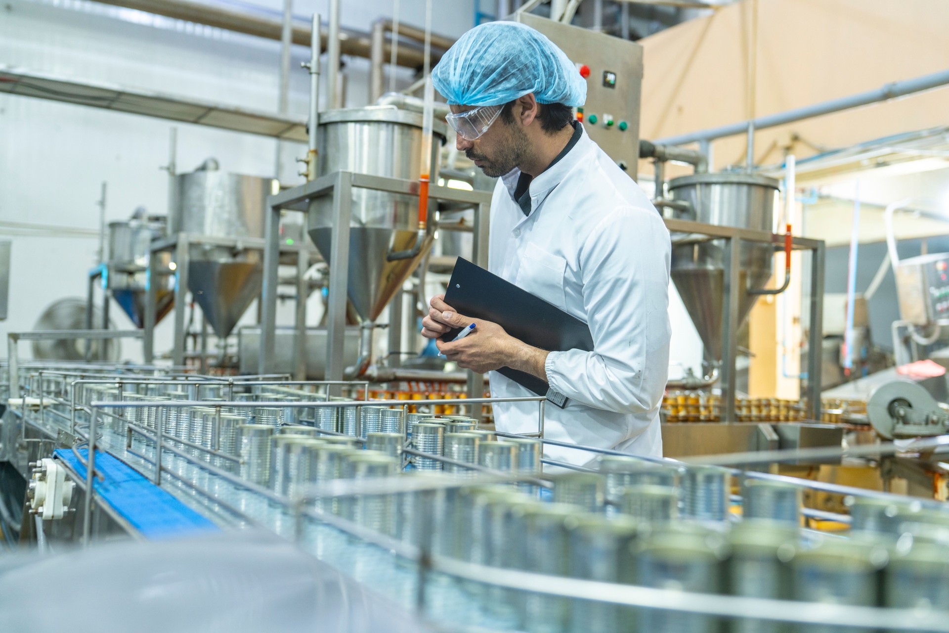 Professional closely examining production materials on a conveyor system, representing dedication to quality, precision, and modern technology in manufacturing processes.