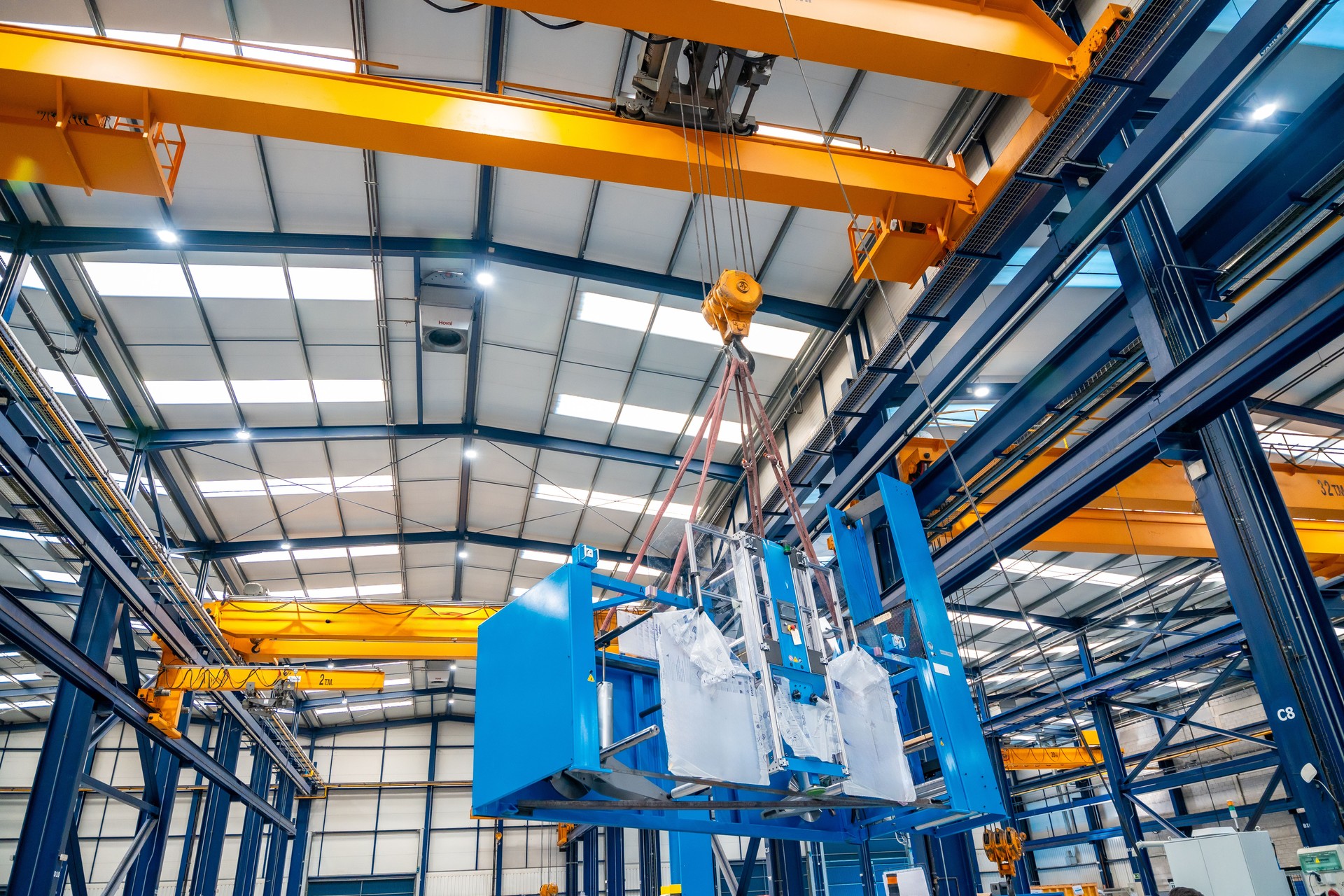 A huge crane lifting heavy machinery indoors